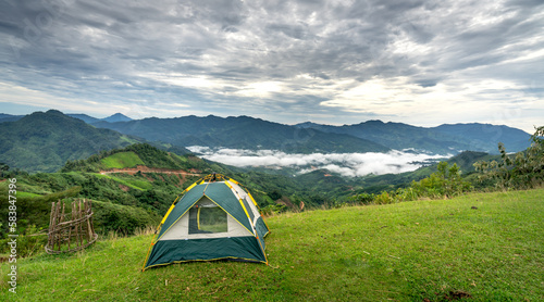 Nam Tra My District, Quang Nam Province, Vietnam - Female tourist with her tent camping on the top of a mountain, a valley of white clouds floating in the early morning.  photo