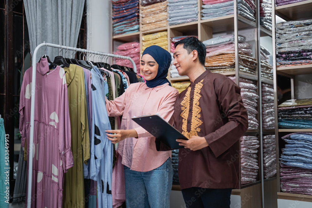 asian muslim woman and man checking their fashion product at the shop asian muslim woman and man checking their fashion product at the shop
