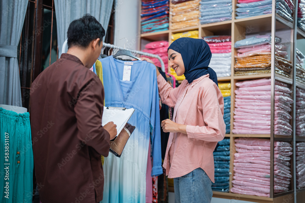 asian muslim woman and man checking their fashion product at the shop