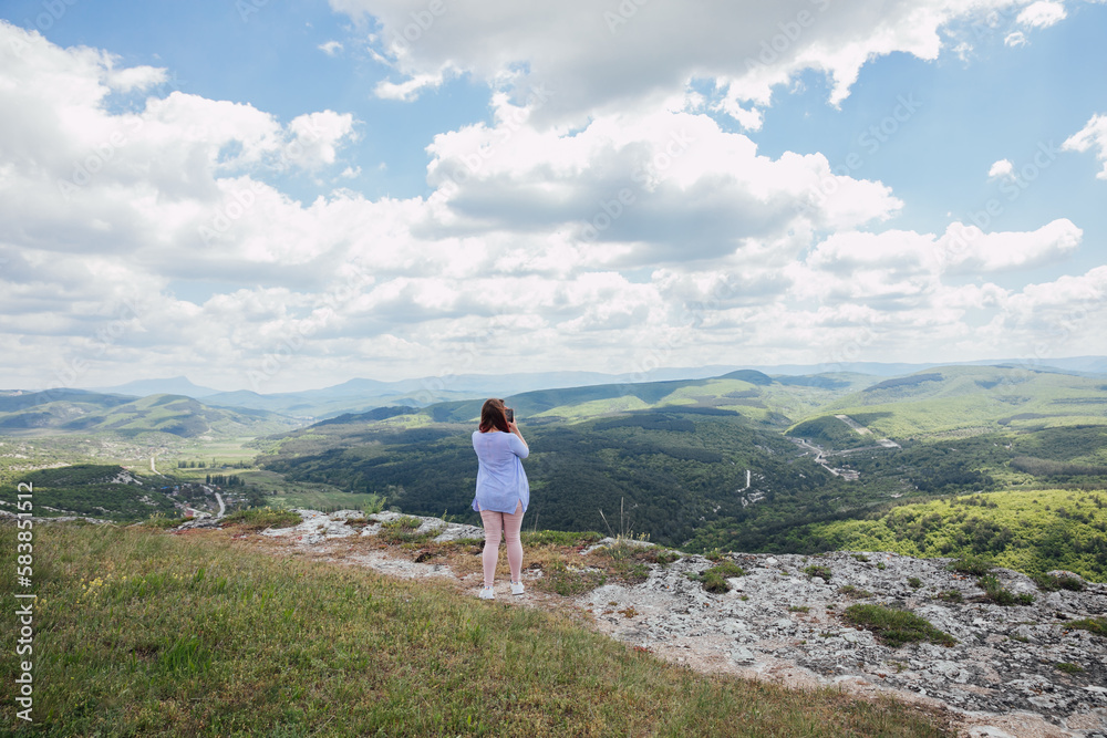 Obraz premium a woman on the mountain looks into the distance admiring nature journey hiking