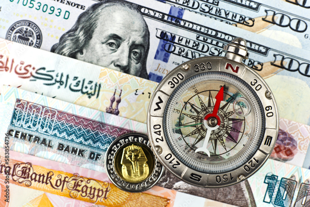 Compass with arrow pointing up on the background of Egyptian pounds and American dollars Compass with arrow pointing up on the background of Egyptian pounds and American dollars