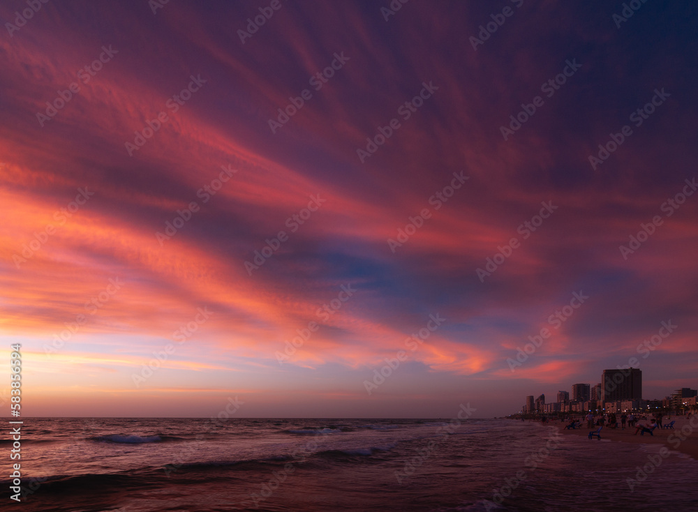 Bat Yam, Israel - May 16, 2020: Sunset over Israel, sea shore, sandy beach, colorful sky