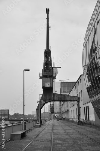 Vertical grayscale shot of an old cargo crane in the Media Harbor in Dusseldorf, Germany.