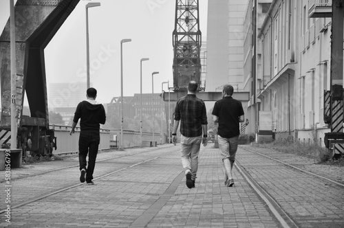 Grayscale shot of three men walking on the quay of the Media Harbor in Dusseldorf, Germany. photo