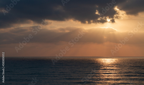Seascape: sunrays break through the clouds on the water surface