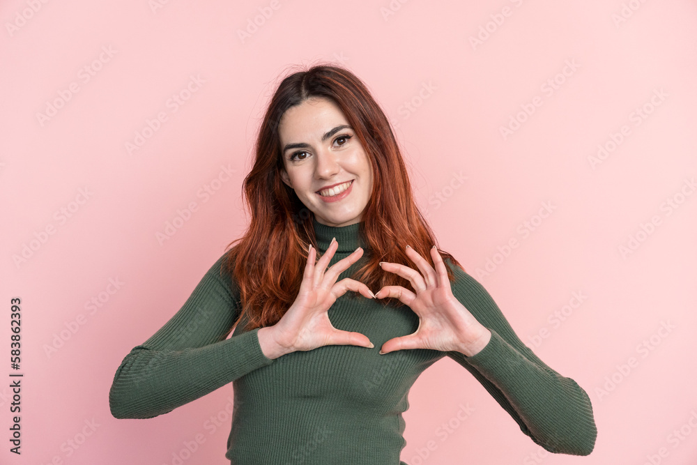 Smiling woman in sweater showing heart gesture Smiling woman in sweater showing heart gesture