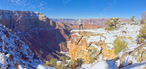 A hiker standing on a snowy cliff on the east rim of Grand Canyon National Park, UNESCO World Heritage Site, Arizona