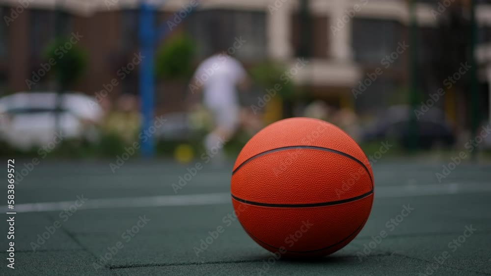 Closeup sports ball with blurred sportsman working out at background on basketball court