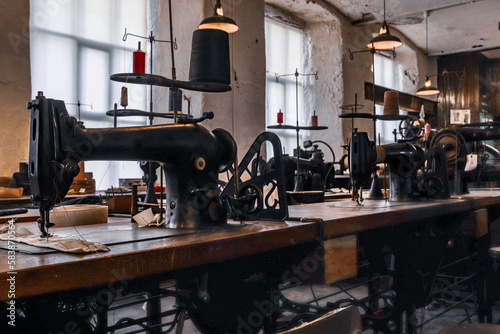 Old sewing black machines on the wood table in factory in Industrial Museum