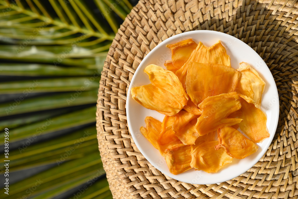 Jackfruit chips in white plate on tropical background with leaf. Vegan sugar free fruits chips