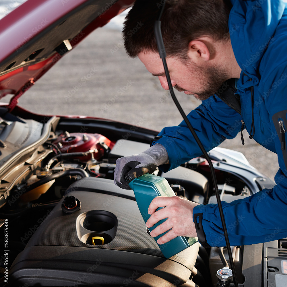 A man with a bottle of motor oil who wants to add oil to his engine A man with a bottle of motor oil who wants to add oil to his engine