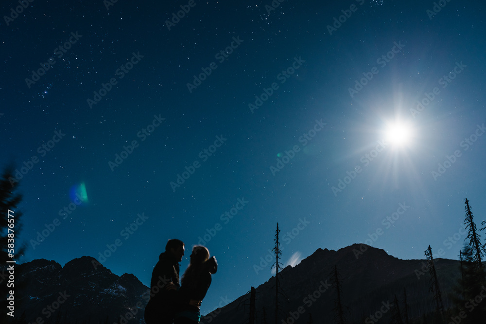 Couple, man and girl together, under the stars, holding hands and kissing. Inspiration. Night mountains.