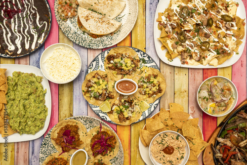 Plate set with Mexican food recipes with tacos of all kinds on wheat and corn tortillas, quesadillas, wire stew, ceviche, grated cheese and colored table