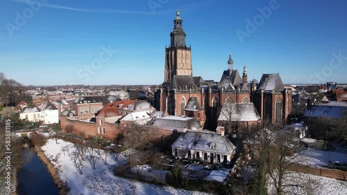 Ascending aerial movement with the Walburgiskerk cathedral of medieval Hanseatic Dutch tower town Zutphen in the Netherlands covered in snow rising above historic heritage cityscape photo