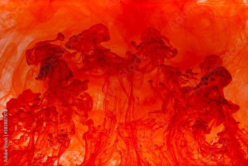 Red paint dissolving in water creating abstract shapes 