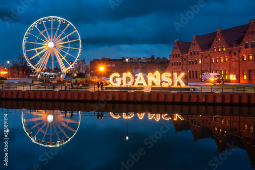 Illuminated name of the city of Gdansk on the Motlawa River at dusk, Poland