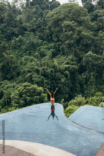 Woman with hands raised standing in swimming pool