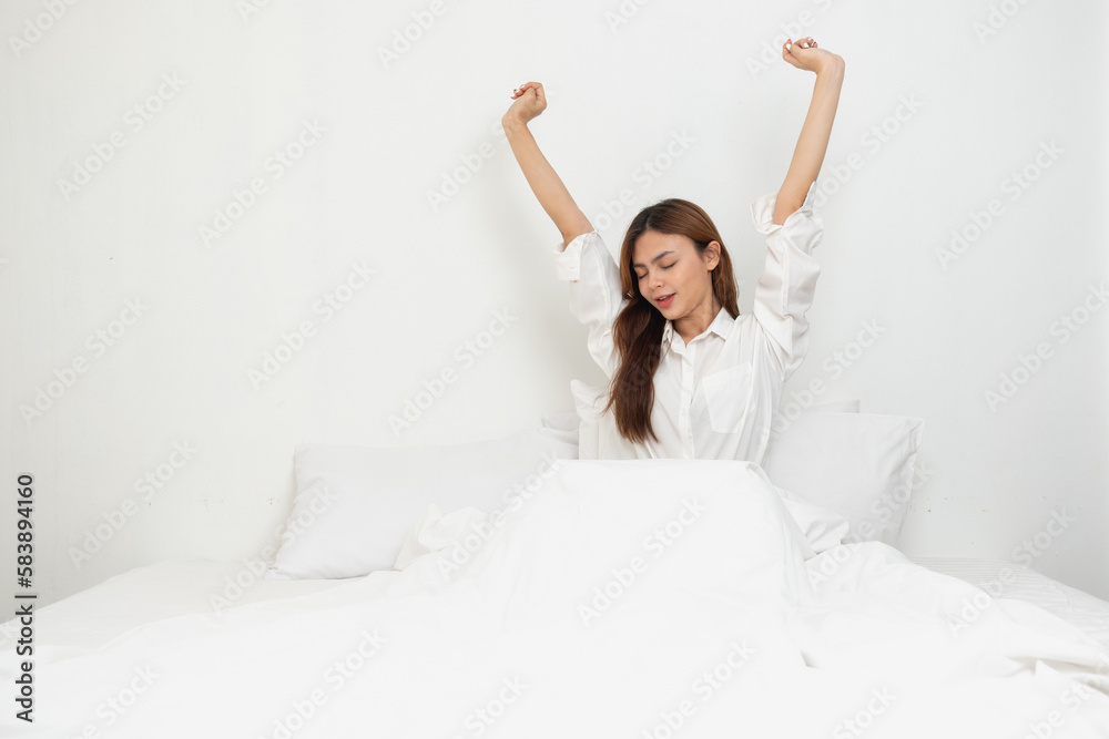 Woman in white nightgown waking up on weekend morning resting and relaxing playing with laptop mobile phone Eating bread and drinking tea in glass inside white bedroom. Morning vacation concept. Woman in white nightgown waking up on weekend morning resting and relaxing playing with laptop mobile phone Eating bread and drinking tea in glass inside white bedroom. Morning vacation concept.