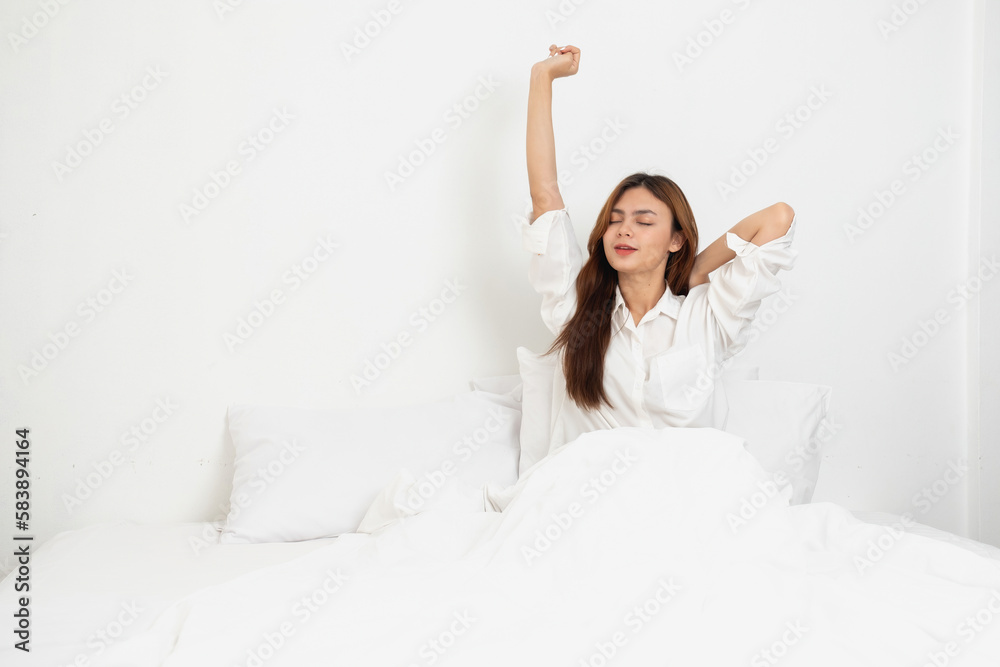 Woman in white nightgown waking up on weekend morning resting and relaxing playing with laptop mobile phone Eating bread and drinking tea in glass inside white bedroom. Morning vacation concept. Woman in white nightgown waking up on weekend morning resting and relaxing playing with laptop mobile phone Eating bread and drinking tea in glass inside white bedroom. Morning vacation concept.