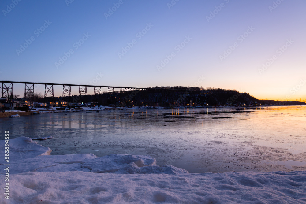 The St. Lawrence river, the 1908 railway trestle bridge and the Cap-Rouge bay seen during a blue hour late winter sunrise, Quebec City, Quebec, Canada 
