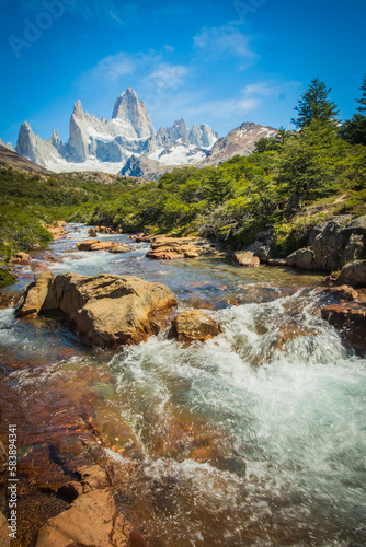 Monte Fitz Roy Landscape, Patagonian Mountain in Argentina and Chilean Patagonia Snowy Peak and Clean River Water Flow during Summer Time, Green Bushes photo