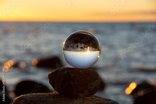 Canvas Print The glass ball lies on the top stone reflecting the beach and the sea