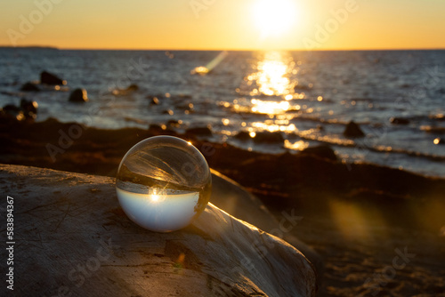Ball made of glass lies on a stone in which the beach and the sea are reflected © Claudia Evans 