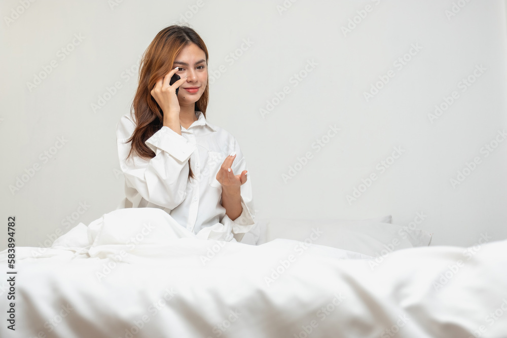 Woman in white nightgown waking up on weekend morning resting and relaxing playing with laptop mobile phone Eating bread and drinking tea in glass inside white bedroom. Morning vacation concept. Woman in white nightgown waking up on weekend morning resting and relaxing playing with laptop mobile phone Eating bread and drinking tea in glass inside white bedroom. Morning vacation concept.