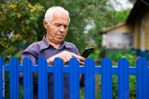 Elderly man writes message on smartphone. Concept of using digital gadgets by elderly