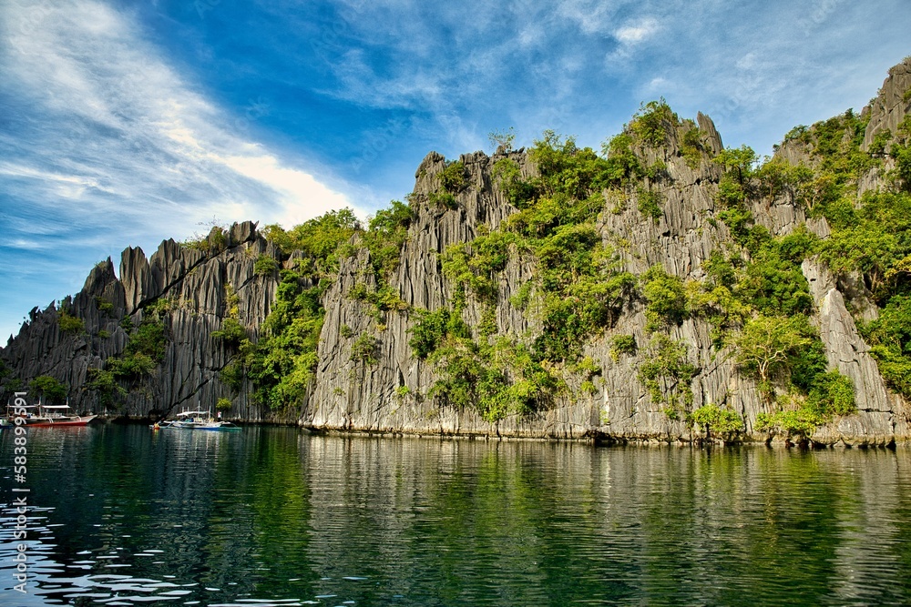 Majestic rocks in Coron, Palawan in the Philippines that are overgrown with shrubs and rise out of the water.