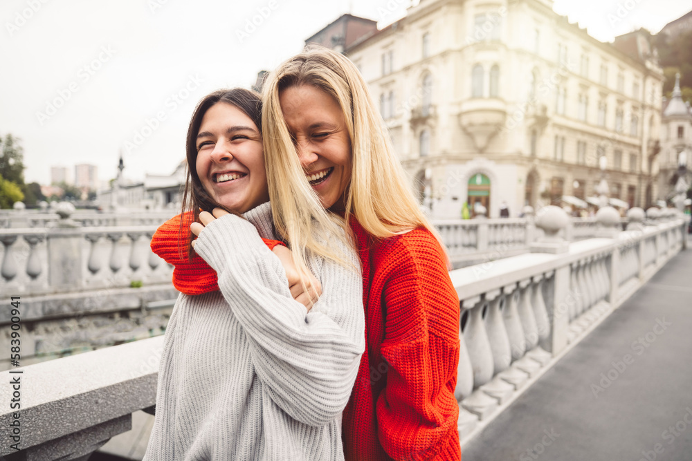 Obraz premium Smiling couple of best friends waist up, hugging on the city streets, sun flare in the corner 