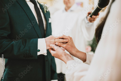 Zakładanie obrączek ślubnych w kościele przez parę młodą