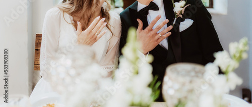 Beautiful bride and groom share a tender kiss, surrounded by flowers and love photo