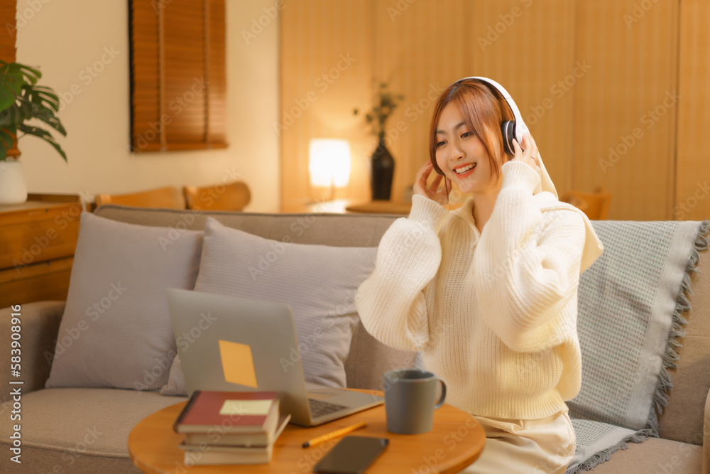 Winter season concept, Young woman wearing headphone to listening music on laptop in night time Winter season concept, Young woman wearing headphone to listening music on laptop in night time