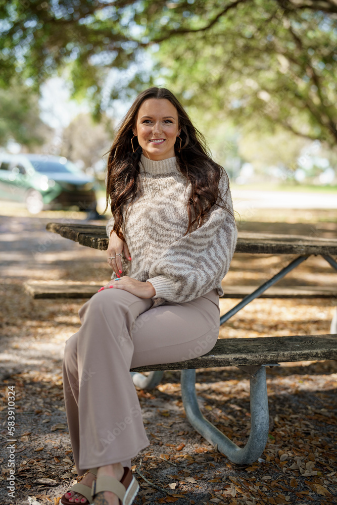 Beautiful young female model posing in the park in the animal print sweater Beautiful young female model posing in the park in the animal print sweater