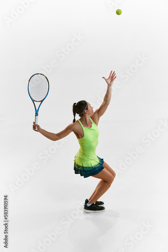 Serving ball. Top view image. Portrait of young woman, professional female tennis player training against white studio background. Concept of professional sport, movement, health, action. Ad