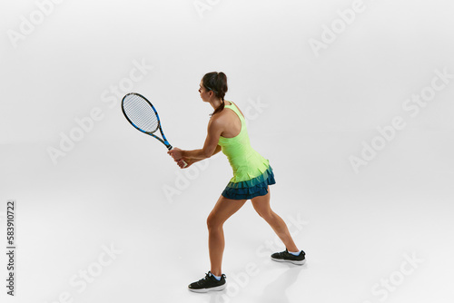 Portrait of young woman, professional female tennis player with racket against white studio background. Ready to play. Concept of professional sport, movement, health, action. Ad