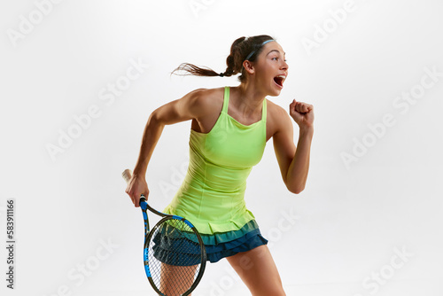 Happiness. Winner. Portrait of young woman, professional female tennis player in uniform posing with tennis racket against white studio background. Concept of professional sport, movement, action. Ad © master1305