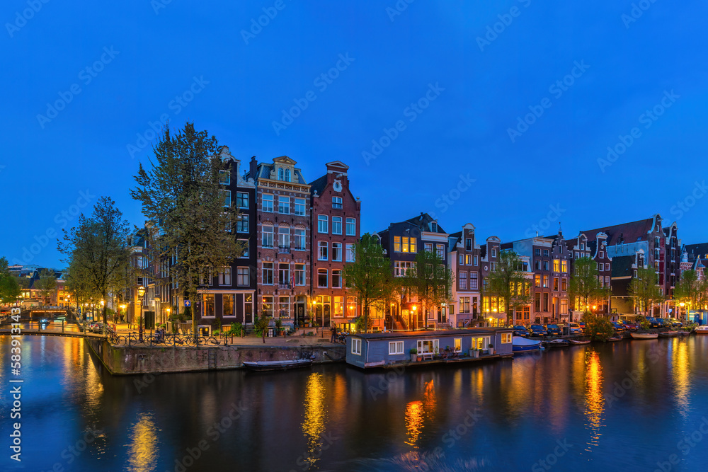 Naklejka premium Amsterdam Netherlands, night city skyline at canal waterfront