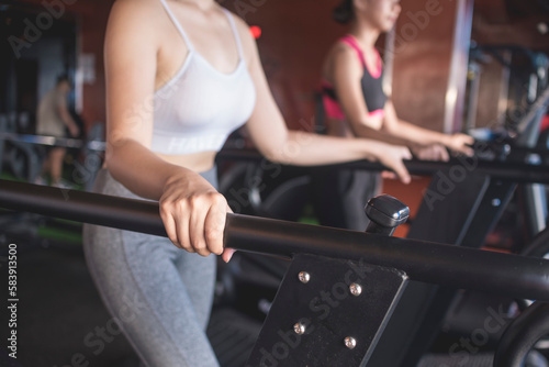 Two anonymous women warming up walking on the treadmill. Working out at the gym.