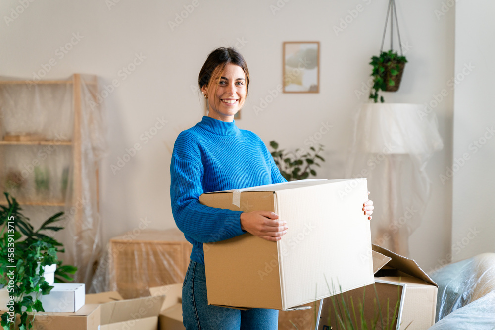 female in casual clothes smiling while standing near shelves with carton boxes female in casual clothes smiling while standing near shelves with carton boxes