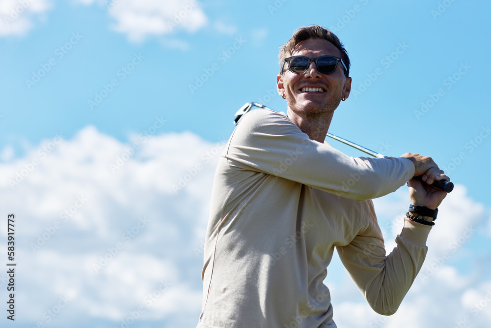 Waist up portrait of smiling man playing golf and swinging golf club against blue sky outdoors, copy space Waist up portrait of smiling man playing golf and swinging golf club against blue sky outdoors, copy space