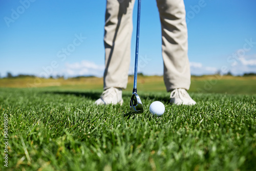 Low section of unrecognizable man playing golf on green grass, focus on ball, copy space
