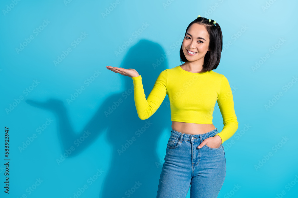 Picture of young japanese cute lady stylish outfit hold hand palm demonstrate advertise mockup new cheap product isolated on blue color background Picture of young japanese cute lady stylish outfit hold hand palm demonstrate advertise mockup new cheap product isolated on blue color background