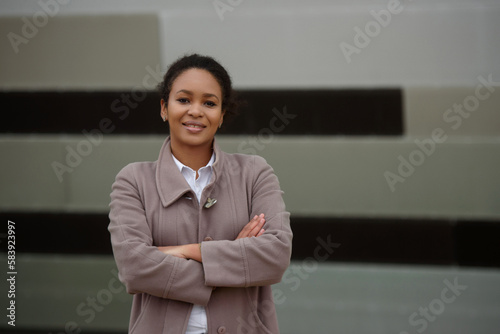 Portrait of smiling young african american woman with arms crossed on chest outside