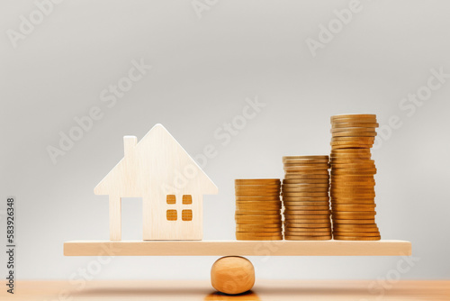 Wooden house on stack of coins isolated