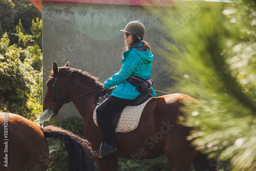 Woman riding horse by stone wall in countryside photo