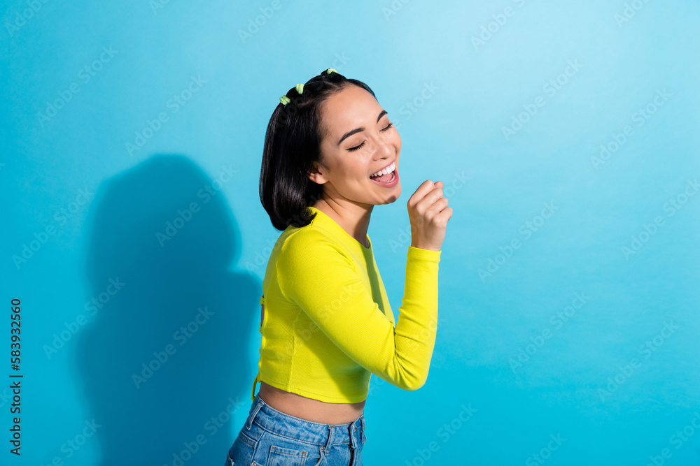 Profile photo of lovely positive girl arm hold imagine microphone sing rejoice isolated on blue color background Profile photo of lovely positive girl arm hold imagine microphone sing rejoice isolated on blue color background