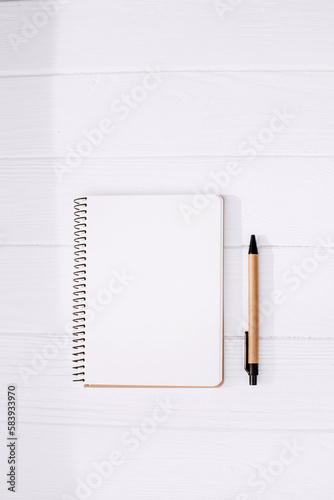 Signature template. An open notepad with a blank sheet and a pen made of eco materials on a white wooden background. Flat lay