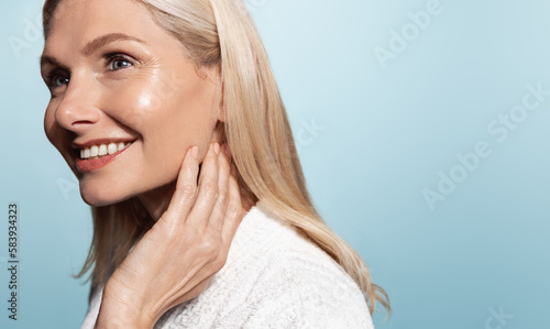 Beautiful 50s mid aged mature woman looking at camera isolated on blue. Mature old lady close up portrait. Healthy face skin care, middle age skincare cosmetics, cosmetology concept